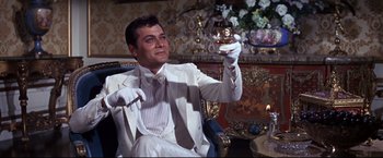 Movie still from “The Great Race” (1965), directed by Blake Edwards – A man in a white suit holding up a glass; Medium shot, Low angle