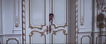 Movie still from “The Great Race” (1965), directed by Blake Edwards – A man peeks out from behind a white door; Medium shot, Low angle