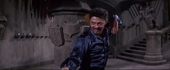 Movie still from “The Great Race” (1965), directed by Blake Edwards – A man in a blue shirt is smiling and posing for a picture; Medium shot, Low angle