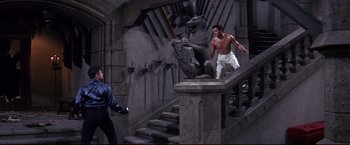 Movie still from “The Great Race” (1965), directed by Blake Edwards – A man in white pants and a blue shirt standing on a staircase; Wide shot, High angle