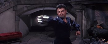 Movie still from “The Great Race” (1965), directed by Blake Edwards – A man in a black shirt is holding something in his hand; Medium shot, Low angle