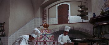 Movie still from “The Great Race” (1965), directed by Blake Edwards – Two men in chef's hats standing in front of a cake; Wide shot, High angle