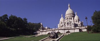 Movie still from “The Great Race” (1965), directed by Blake Edwards – A car driving down a road next to a building with domes; Extreme Wide shot, High angle