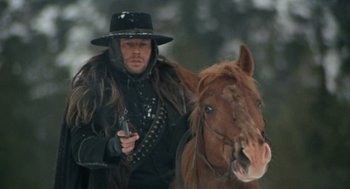 Movie still from “The Great Silence” (1968), directed by Sergio Corbucci – A man holding a gun while standing next to a horse; Close Up shot, Low angle