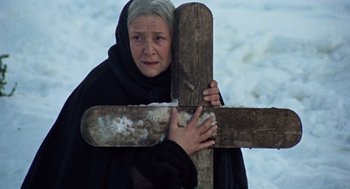 Movie still from “The Great Silence” (1968), directed by Sergio Corbucci – An older woman holding a cross in the snow; Close Up shot, Low angle