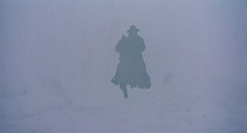 Movie still from “The Great Silence” (1968), directed by Sergio Corbucci – A shadow of a person in a hat and coat; Wide shot, Low angle