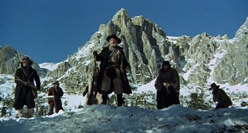 Movie still from “The Great Silence” (1968), directed by Sergio Corbucci – A group of men standing on top of a snow covered slope; Wide shot, Low angle