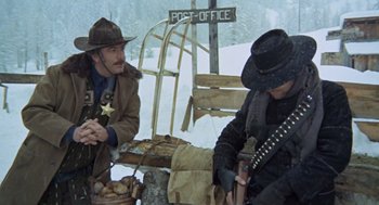 Movie still from “The Great Silence” (1968), directed by Sergio Corbucci – Two men sitting on a bench in the snow; Wide shot, Low angle