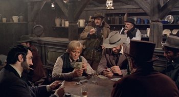 Movie still from “The Great Silence” (1968), directed by Sergio Corbucci – A group of men sitting around a table playing cards; Medium shot, Over the shoulder angle