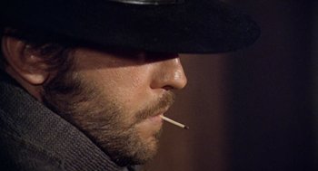 Movie still from “The Great Silence” (1968), directed by Sergio Corbucci – A person wearing a hat and smoking a cigarette; Close Up shot, Low angle