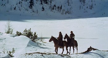 Movie still from “The Great Silence” (1968), directed by Sergio Corbucci – A couple of men riding on the backs of horses in the snow; Extreme Wide shot, High angle
