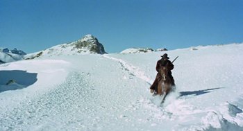 Movie still from “The Great Silence” (1968), directed by Sergio Corbucci – A man riding on the back of a horse through the snow; Wide shot, Low angle