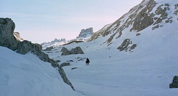 Movie still from “The Great Silence” (1968), directed by Sergio Corbucci – A person riding skis on top of a snow covered slope; Extreme Wide shot, Low angle