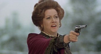 Movie still from “The Great Silence” (1968), directed by Sergio Corbucci – An older woman is holding a gun and pointing it; Close Up shot, Over the shoulder angle