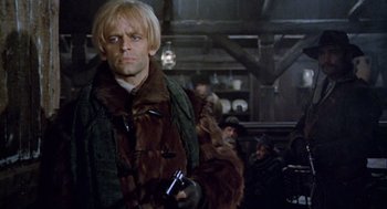 Movie still from “The Great Silence” (1968), directed by Sergio Corbucci – A man with blonde hair holding a cell phone; Medium shot, Over the shoulder angle
