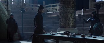 Movie still from “The Great Wall” (2016), directed by Yimou Zhang – A man standing in front of a table with an object on top of it; Wide shot, Low angle