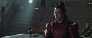 Movie still from “The Great Wall” (2016), directed by Yimou Zhang – A man in a red outfit is standing in a room; Medium shot, Over the shoulder angle