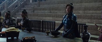 Movie still from “The Great Wall” (2016), directed by Yimou Zhang – A woman sitting at a table with a bowl of food; Medium shot, Over the shoulder angle