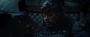 Movie still from “The Great Wall” (2016), directed by Yimou Zhang – A man wearing a helmet and armor in a dark room; Close Up shot, High angle