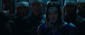 Movie still from “The Great Wall” (2016), directed by Yimou Zhang – A woman with a headband is standing in front of a group of men; Close Up shot, Over the shoulder angle