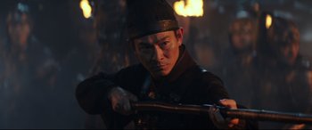 Movie still from “The Great Wall” (2016), directed by Yimou Zhang – A man wearing a hat is holding a sword; Close Up shot, Low angle