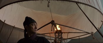 Movie still from “The Great Wall” (2016), directed by Yimou Zhang – A man standing under an umbrella with a flame in it; Medium shot, Low angle