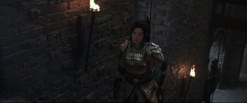Movie still from “The Great Wall” (2016), directed by Yimou Zhang – A woman dressed as a samurai standing next to a brick wall; Medium shot, Over the shoulder angle