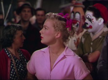 Movie still from “The Greatest Show on Earth” (1952), directed by Cecil B. DeMille – A woman in a pink shirt with a pink bow in her hair; Medium shot, Over the shoulder angle