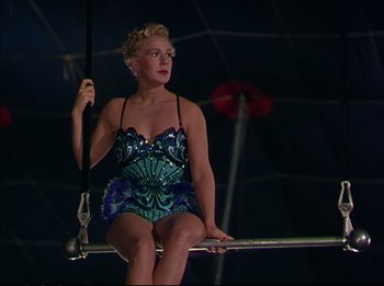 Movie still from “The Greatest Show on Earth” (1952), directed by Cecil B. DeMille – A woman sitting on top of a metal bar; Medium shot, Low angle