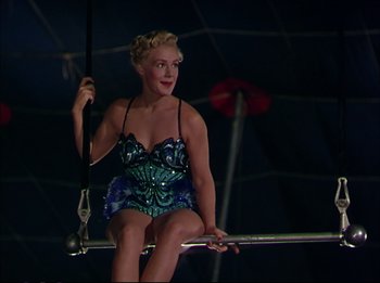 Movie still from “The Greatest Show on Earth” (1952), directed by Cecil B. DeMille – A woman sitting on top of a metal bar; Medium shot, Low angle