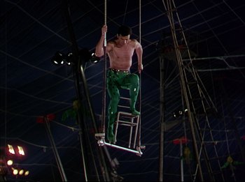 Movie still from “The Greatest Show on Earth” (1952), directed by Cecil B. DeMille – A shirtless man hanging from a metal pole; Wide shot, Low angle