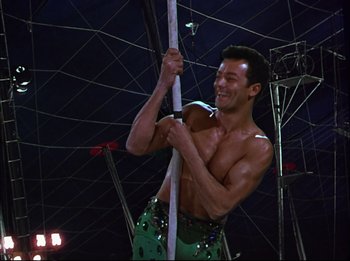 Movie still from “The Greatest Show on Earth” (1952), directed by Cecil B. DeMille – A shirtless man holding onto a pole while standing in the dark; Medium shot, Low angle
