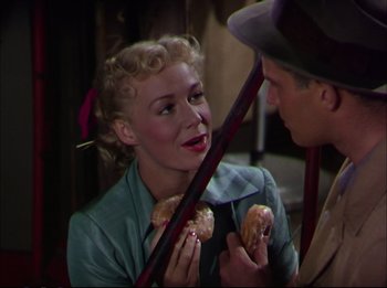 Movie still from “The Greatest Show on Earth” (1952), directed by Cecil B. DeMille – A man and a woman are eating donuts; Medium shot, Overhead angle