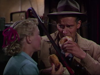 Movie still from “The Greatest Show on Earth” (1952), directed by Cecil B. DeMille – A man and a woman are eating a donut together; Medium shot, Over the shoulder angle