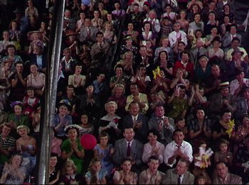Movie still from “The Greatest Show on Earth” (1952), directed by Cecil B. DeMille – A crowd of people sitting and standing in a stadium; Wide shot, High angle