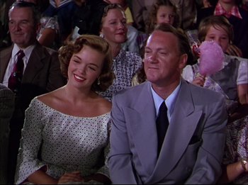 Movie still from “The Greatest Show on Earth” (1952), directed by Cecil B. DeMille – A man and a woman sitting next to each other in a crowd; Medium shot, Low angle
