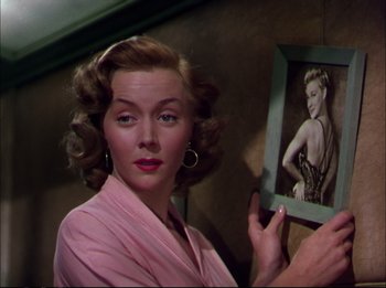 A woman holding a picture of a woman in front of a mirror