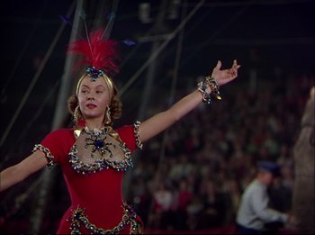 Movie still from “The Greatest Show on Earth” (1952), directed by Cecil B. DeMille – A woman in a red dress and a red feather headdress; Medium shot, Low angle