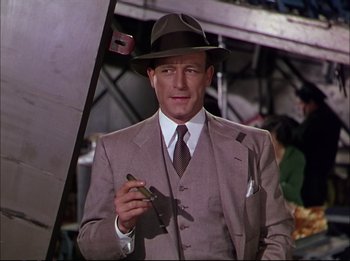 Movie still from “The Greatest Show on Earth” (1952), directed by Cecil B. DeMille – A man in a suit and hat holding a cigarette; Medium shot, Low angle