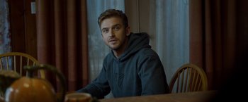 Movie still from “The Guest” (2014), directed by Adam Wingard – A man sitting at a dining table wearing a hoodie; Close Up shot, Over the shoulder angle