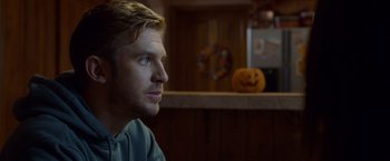 Movie still from “The Guest” (2014), directed by Adam Wingard – A man sitting in front of an orange pumpkin; Close Up shot, Over the shoulder angle