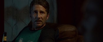 Movie still from “The Guest” (2014), directed by Adam Wingard – A person sitting on a couch; Close Up shot, Over the shoulder angle