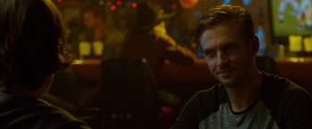Movie still from “The Guest” (2014), directed by Adam Wingard – A man sitting at a table in front of lights; Close Up shot, Over the shoulder angle