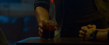 Movie still from “The Guest” (2014), directed by Adam Wingard – A person holding a glass of soda on a table; Extreme Close Up shot, High angle