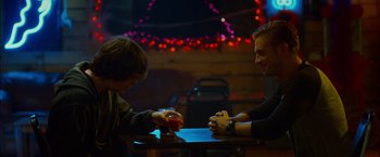 Movie still from “The Guest” (2014), directed by Adam Wingard – Two men sitting at a table playing a game; Medium shot, Over the shoulder angle