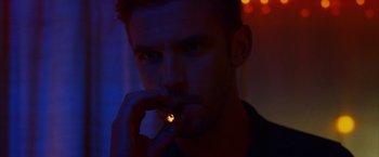 Movie still from “The Guest” (2014), directed by Adam Wingard – A man is smoking a cigarette in a dark room; Close Up shot, Over the shoulder angle