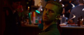Movie still from “The Guest” (2014), directed by Adam Wingard – A person in a room with lights in the background; Close Up shot, Over the shoulder angle
