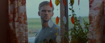 Movie still from “The Guest” (2014), directed by Adam Wingard – A man standing in front of a window with flowers; Close Up shot, Over the shoulder angle