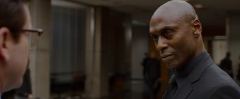 Movie still from “The Guest” (2014), directed by Adam Wingard – A man with a bald head is standing in an office; Close Up shot, Over the shoulder angle