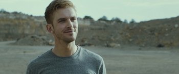 Movie still from “The Guest” (2014), directed by Adam Wingard – A young man is standing in the dirt; Close Up shot, Over the shoulder angle